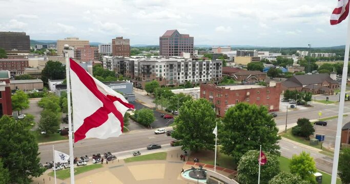 Huntsville, Alabama skyline with Alabama flag flying close up with drone video moving up.