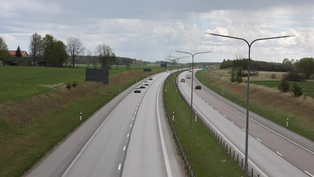 Beautiful top view of E4 highway with several cars. Green side fields and stormy sky background. Sweden.