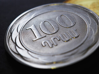 Armenian coins lie on a dark black surface close-up. 100 dram coin. Money of Armenia. News about economy or currency. Loan and credit. Tax and inflation. Macro