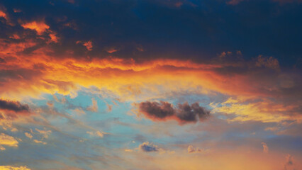 Cloudy sky at sunset. Dark blue and yellow natural background or wallpaper. The rays of the setting sun effectively illuminate the clouds. Beautiful and spectacular setting sky. Nightfall cloudscape