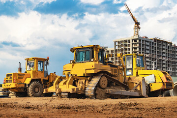 Bulldozer machine is leveling construction site. Earthmover with sky background. close-up. construction heavy machinery.