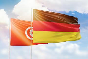 Sunny blue sky and flags of germany and tunisia
