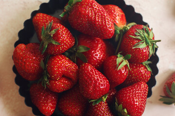 Fresh juicy strawberries in a plate on light stone table