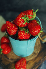 Fresh juicy strawberries on wooden board on dark stone table