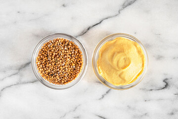 Close-up of mustard seeds and yellow mustard in glass bowls