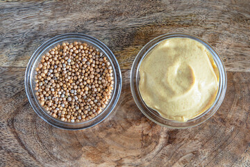 Close-up of mustard seeds and yellow mustard in glass bowls