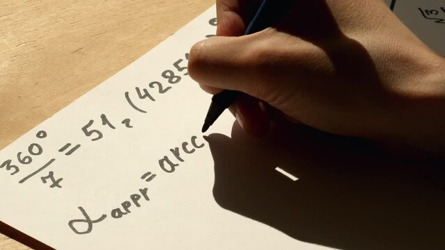 Hand of a young mathematician writing formula with arccos function on white paper. Date of shooting day 10 May 2022 year, MSK time. This video was filmed in Russia.
