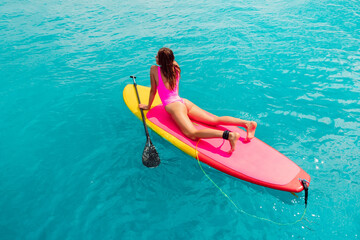 Beautiful woman posing on Paddle board in blue sea. SUP boarding in ocean