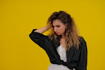 Close-up portrait of a beautiful girl on a yellow background. woman shows thoughtfulness. human emotions