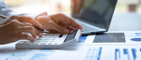 Close up Businessman using calculator and laptop for calculating finance, tax, accounting,...