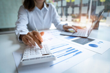 Close up Businessman using calculator and laptop for calculating finance, tax, accounting, statistics and analytic research concept