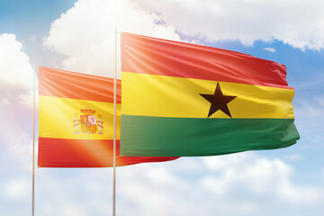 Sunny blue sky and flags of ghana and spain