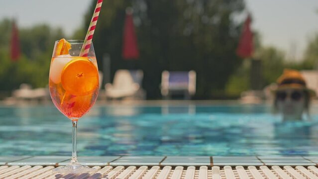 Cold and refreshing aperol spritz cocktail is the perfect summer drink at poolside. Slow motion 4k video.