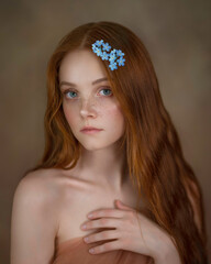 Fine art portrait of a blue-eyed and red-haired girl with forget-me-nots