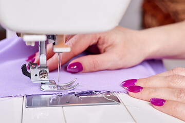 Woman sewing a dress on a sewing machine. Close-up, selective focus
