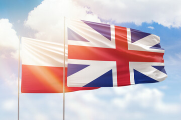 Sunny blue sky and flags of great britain and poland