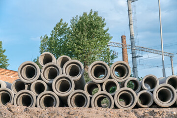 Large heap of cement pipes for engineering and plumbing stacked on construction site or manufacturing plant.
