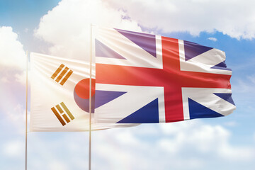 Sunny blue sky and flags of great britain and south korea