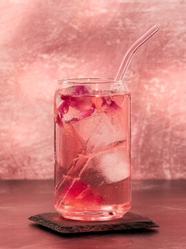 A glass of pink gin and rose lemonade on a pink background, top copy space