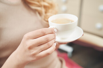 Female is keeping cup of coffee in hands