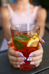 A cocktail with ice in the hands of a girl