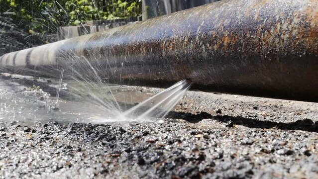 a jet of water and splashes pour from a metal bursting water pipe under high pressure. Depreciation of plumbing equipment leads to utility failures and interruptions in the supply of drinking water