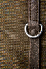 Close-up texture of a canvas fabric backpack. Leather straps and metal buckles. Vintage khaki back.