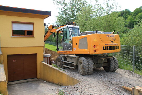 Bagger baggert sehr nah an einer Hauswand