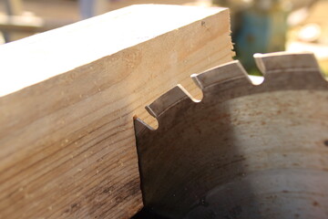 Ein Stück Bauholz liegt am Sägeblatt einer Kreissäge an