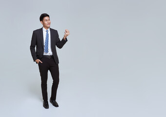 handsome and friendly face asian businessman smile in formal suit and hand holding presented something to copy space on white background studio shot.