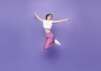 Happy woman smiling and jumping while celebrating success isolated on violet background.