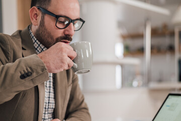 Young entrepreneur drinking coffee while working at office desk