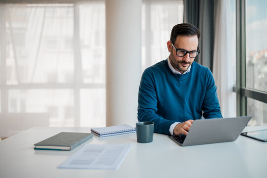 Serious young male professional working on laptop while sitting at office