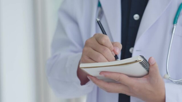 Young doctor writes down a patient's medical history in a notebook. Asian doctor consult pediatrician give advice to patients , Healthcare and medicine concept