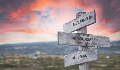 helping yourself heal text quote caption on wooden signpost outdoors in nature with dramatic sunset...