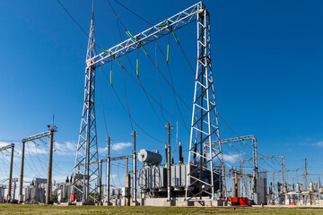 High voltage power transformer substation against the blue sky. - obrazy, fototapety, plakaty