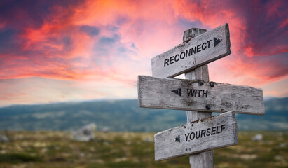 reconnect with yourself text quote caption on wooden signpost outdoors in nature with dramatic sunset skies. Panorama crop. - obrazy, fototapety, plakaty