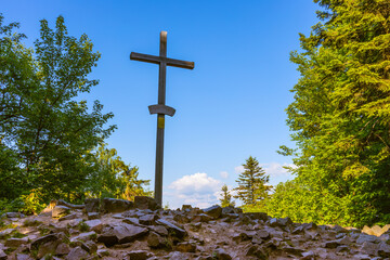 Lysica Mount peak with memorial cross near Swieta Katarzyna village and Bodzentyn at tourist path across Swietokrzyskie Mountains in Poland - obrazy, fototapety, plakaty
