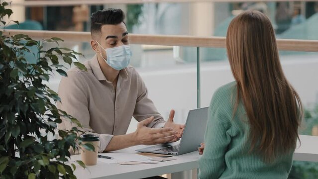 Arabic boss leader hr manager in medical mask lead interview with female candidate shaking hands for job invite. Indian male consultant man bank worker advising female client agree handshaking union
