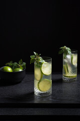 Dos vasos de refrescante zumo de lima con rodajas de lima y hielo sobre fondo negro