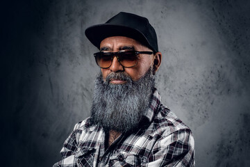 Portrait of cool old man hipster with beard dressed in plaid shirt and baseball cap.