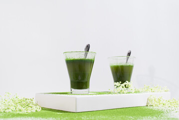 Dos vasos de té matcha con polvo de té verde espolvoreado sobre una mesa blanca	