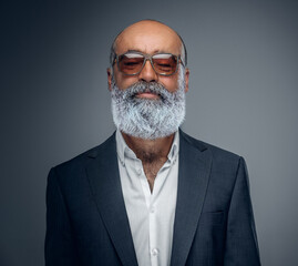 Shot of elderly businessperson with beard and sunglasses dressed in stylish suit.