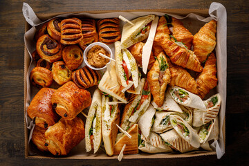 Various snacks in a cardboard box. Set of sandwiches, vegetables, sauces and canapes.