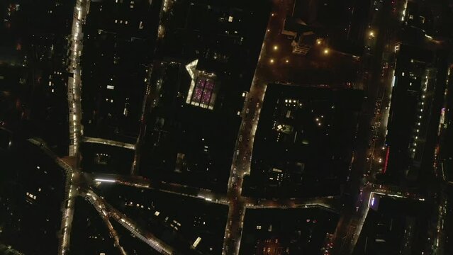 Top down static shot of illuminated streets and blocks of buildings in night city. Cars driving on road and passing intersections. Cologne, Germany