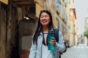 Young woman in the city walking with a water bottle