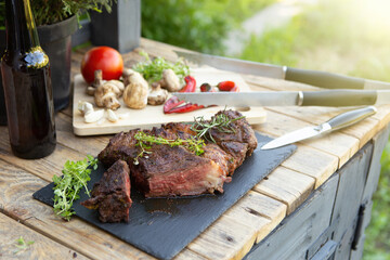 Grilled beef steak on wooden table top. Healthy food concept. Beef cut outdoors, garden kitchen,...