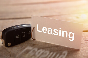 Car Leasing concept. Vehicle security key with tag on the wooden background