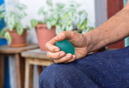  Asian elder man gripping hand exercise elastic ball.