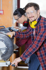 foreman training female worker to use circular saw